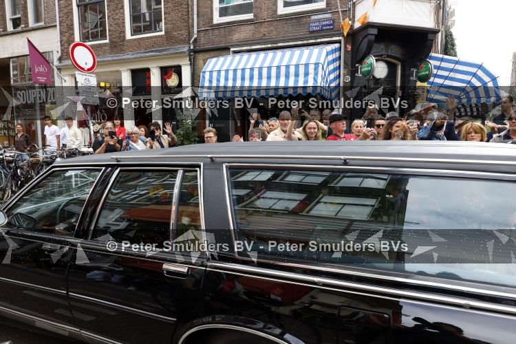 Amsterdam 17 augustus 2026
De stoet met Peter faber rijdt onder politiebegeleiding over de Haarlemmerstraat langs zijn favoriete cafe\'s . Vele mensen bewijzen hem een laatste eer.
