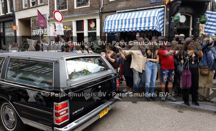 Amsterdam 17 augustus 2026
De stoet met Peter faber rijdt onder politiebegeleiding over de Haarlemmerstraat langs zijn favoriete cafe\'s . Vele mensen bewijzen hem een laatste eer.