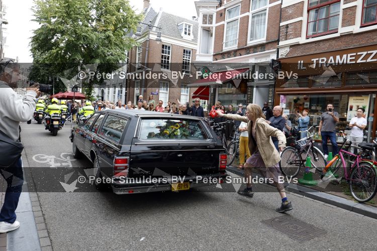 Amsterdam 17 augustus 2026
De stoet met Peter faber rijdt onder politiebegeleiding over de Haarlemmerstraat langs zijn favoriete cafe\'s . Vele mensen bewijzen hem een laatste eer.