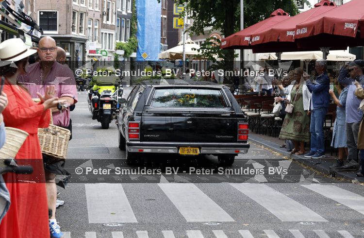 Amsterdam 17 augustus 2026
De stoet met Peter faber rijdt onder politiebegeleiding over de Haarlemmerstraat langs zijn favoriete cafe\'s . Vele mensen bewijzen hem een laatste eer.