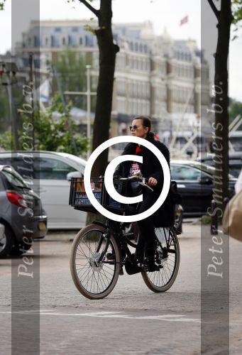 Amsterdam 20 juni 2015  
Trijntje Oosterhuis met zoontje op de fiets in Amsterdam. Trijntje gaat een huis binnen en ze geeft een toerist uitleg over hoe waar naartoe te lopen.