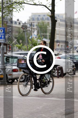 Amsterdam 20 juni 2015  
Trijntje Oosterhuis met zoontje op de fiets in Amsterdam. Trijntje gaat een huis binnen en ze geeft een toerist uitleg over hoe waar naartoe te lopen.