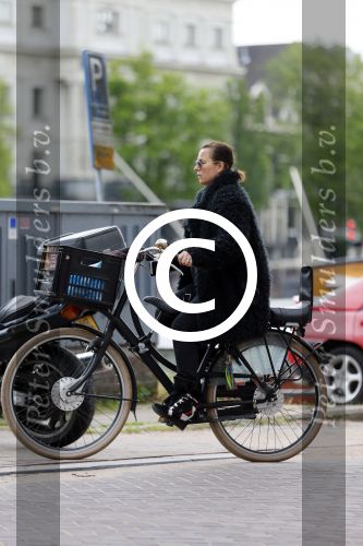 Amsterdam 20 juni 2015  
Trijntje Oosterhuis met zoontje op de fiets in Amsterdam. Trijntje gaat een huis binnen en ze geeft een toerist uitleg over hoe waar naartoe te lopen.