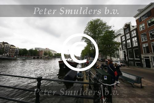 Amsterdam 20 juni 2015  
Trijntje Oosterhuis met zoontje op de fiets in Amsterdam. Trijntje gaat een huis binnen en ze geeft een toerist uitleg over hoe waar naartoe te lopen.