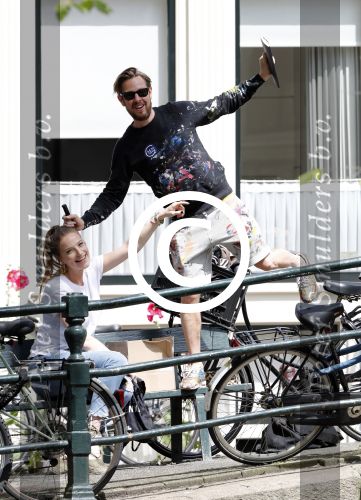 Amsterdam 13 juli 2016  
Selwyn Senatori zit samen met zijn vriendin op bankje zijn boek te signeren als haar fiets omvalt en haarvtas met mobieltje etc het water in valt . Een rondvaartboot vist alles eruit