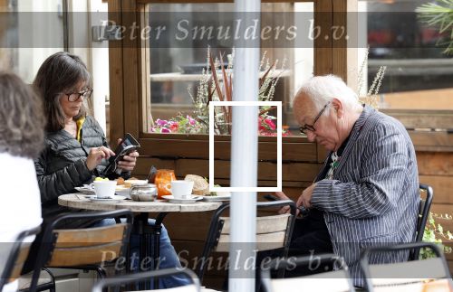 Amsterdam 1 juli 2024
Youp van t Hek en zijn vrouw Debby Petter op terras en op de fiets in Amsterdam zuid. Ze zijn beide druk op hun telefoon.