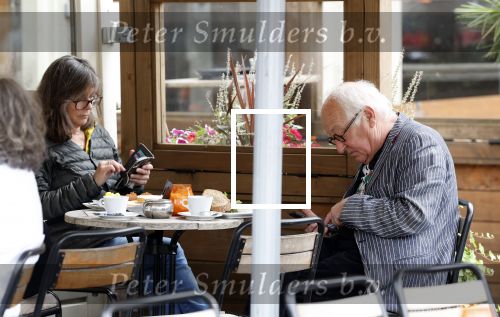 Amsterdam 1 juli 2024
Youp van t Hek en zijn vrouw Debby Petter op terras en op de fiets in Amsterdam zuid. Ze zijn beide druk op hun telefoon.
