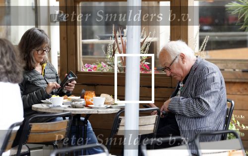Amsterdam 1 juli 2024
Youp van t Hek en zijn vrouw Debby Petter op terras en op de fiets in Amsterdam zuid. Ze zijn beide druk op hun telefoon.