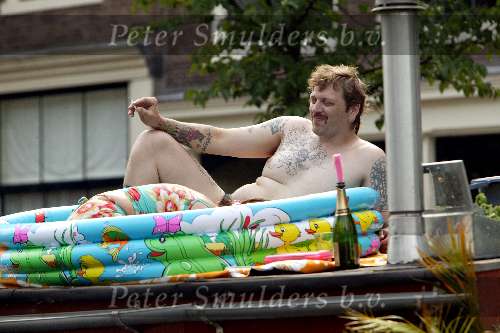 Amsterdam 16 juli 2003
Maan met tatoeage  zit in plastic zwembadje op woonboot