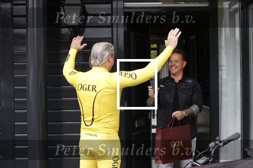 Purmerend 16 mei 2020
Dries Roelvink brengt op de fiets in een gele wielrentrui/broek een pakketje van OGER naar Danny de Munk die thuyis de deur opent als dries aan belt .