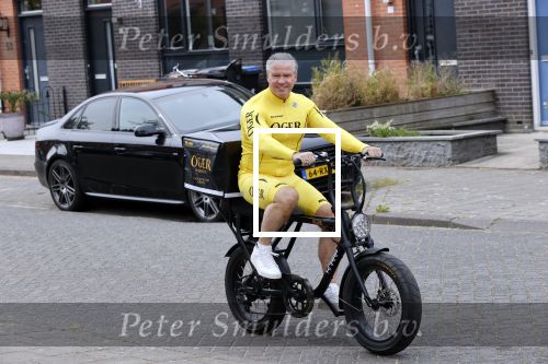 Purmerend 16 mei 2020
Dries Roelvink brengt op de fiets in een gele wielrentrui/broek een pakketje van OGER naar Danny de Munk die thuyis de deur opent als dries aan belt .