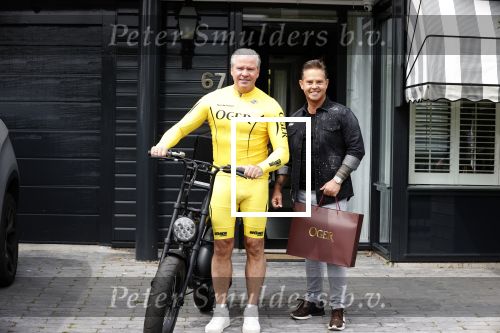 Purmerend 16 mei 2020
Dries Roelvink brengt op de fiets in een gele wielrentrui/broek een pakketje van OGER naar Danny de Munk die thuyis de deur opent als dries aan belt .