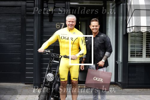 Purmerend 16 mei 2020
Dries Roelvink brengt op de fiets in een gele wielrentrui/broek een pakketje van OGER naar Danny de Munk die thuyis de deur opent als dries aan belt .