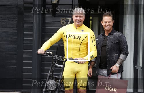 Purmerend 16 mei 2020
Dries Roelvink brengt op de fiets in een gele wielrentrui/broek een pakketje van OGER naar Danny de Munk die thuyis de deur opent als dries aan belt .