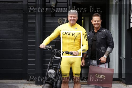 Purmerend 16 mei 2020
Dries Roelvink brengt op de fiets in een gele wielrentrui/broek een pakketje van OGER naar Danny de Munk die thuyis de deur opent als dries aan belt .