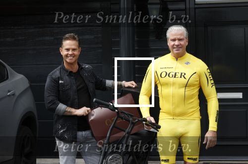 Purmerend 16 mei 2020
Dries Roelvink brengt op de fiets in een gele wielrentrui/broek een pakketje van OGER naar Danny de Munk die thuyis de deur opent als dries aan belt .