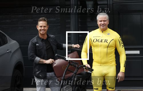 Purmerend 16 mei 2020
Dries Roelvink brengt op de fiets in een gele wielrentrui/broek een pakketje van OGER naar Danny de Munk die thuyis de deur opent als dries aan belt .