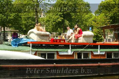 Woonboot aan grachten van Amsterdam
Sloepenroute
Bankstel met daarop mensen die een hapje eten en een glaasje drinken