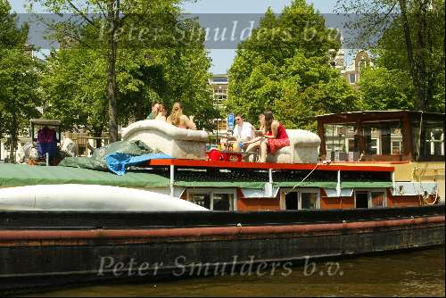 Woonboot aan grachten van Amsterdam
Sloepenroute
Bankstel met daarop mensen die een hapje eten en een glaasje drinken