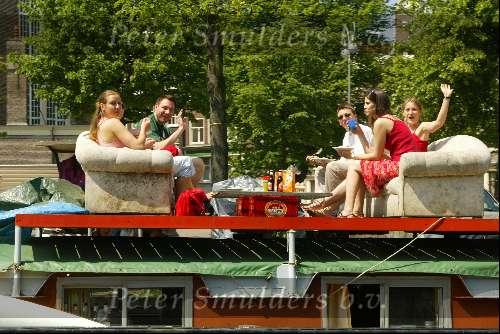 Woonboot aan grachten van Amsterdam
Sloepenroute
Bankstel met daarop mensen die een hapje eten en een glaasje drinken