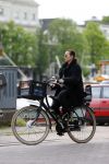 Amsterdam 20 juni 2015  
Trijntje Oosterhuis met zoontje op de fiets in Amsterdam. Trijntje gaat een huis binnen en ze geeft een toerist uitleg over hoe waar naartoe te lopen.