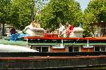 Woonboot aan grachten van Amsterdam
Sloepenroute
Bankstel met daarop mensen die een hapje eten en een glaasje drinken